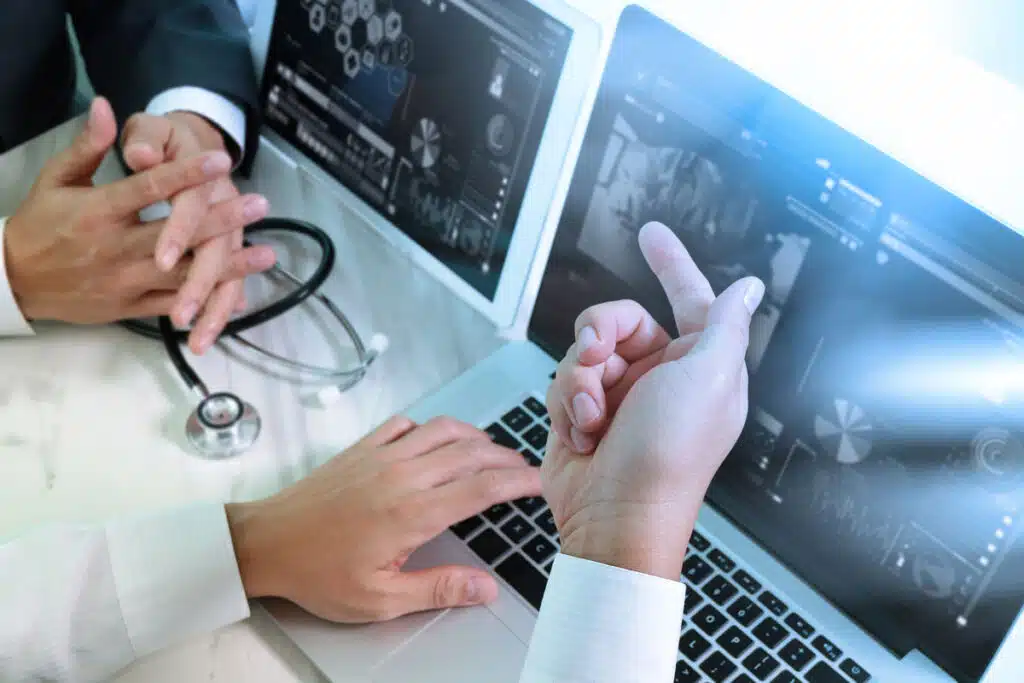 Close up of two doctors hands reviewing medical exams on a laptop, representing the Conway Regional Medical Center data breach settlement.
