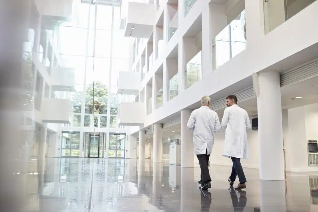 Rear View Of Doctors Talking As They Walk Through Hospital, representing the Universal Health Services (UHS) ERISA class action lawsuit settlement.