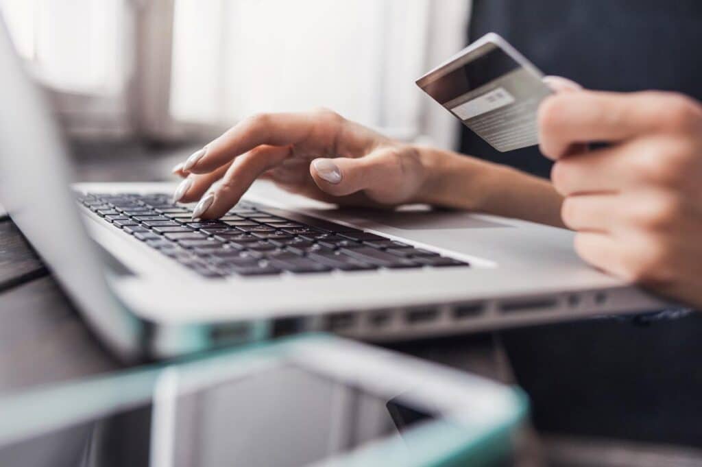 Close up of a womans hands holding a credit card as she types on a laptop. Online shopping concept.