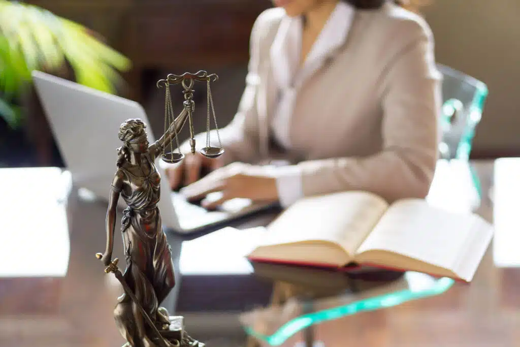 Close up of Justice status in front of a lawyer working at her desk, representing the PACER fees settlement.
