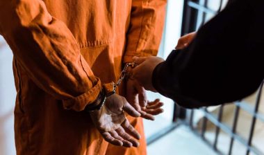 Close up of an officer putting handcuffs on a prisoner, representing the New York City bail over-detention settlement.
