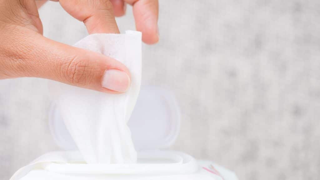 Close up of a womans hands pulling a wipe out of a package.