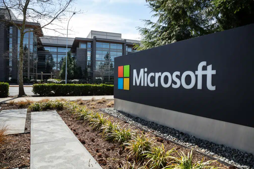 Wide angle view of a Microsoft sign at the headquarters for the software and hardware company, with office building in the background.