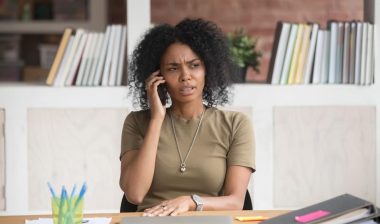 A frustrated young woman talking on the phone, representing the Highmark Health class action lawsuit settlement.
