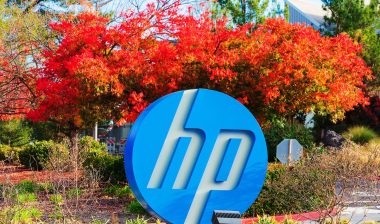 Blue, white round HP logo of Hewlett-Packard Company in front of foilage, representing the HP equal pay class action lawsuit settlement.