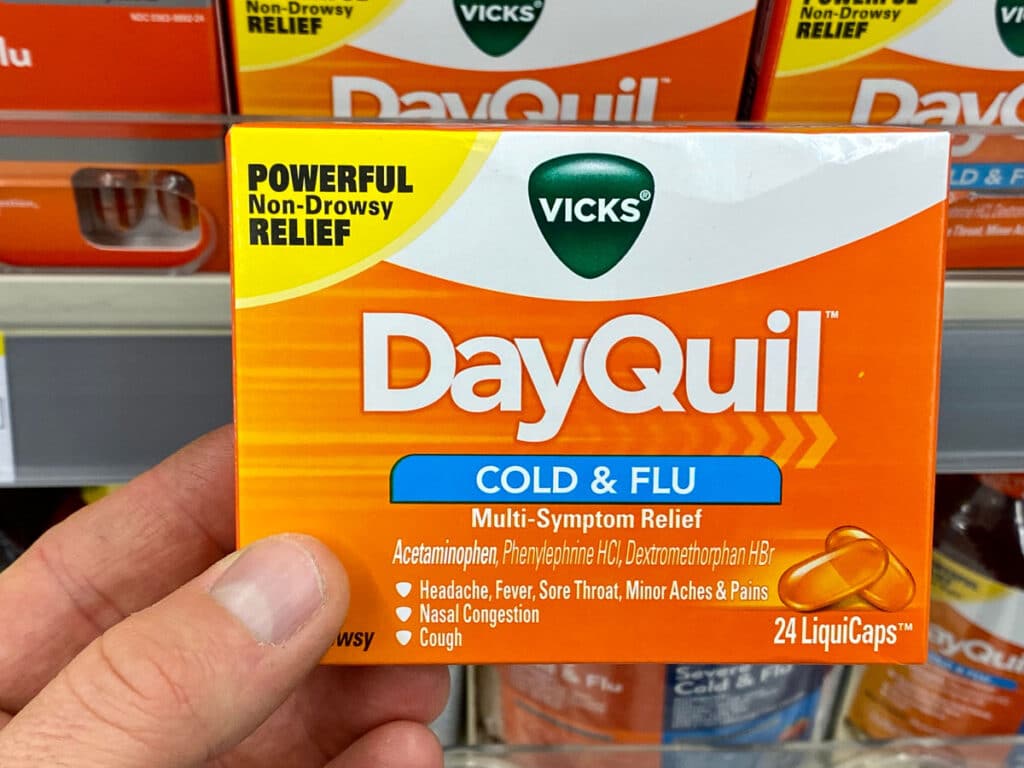Close up of a hand holding a box of DayQuil.