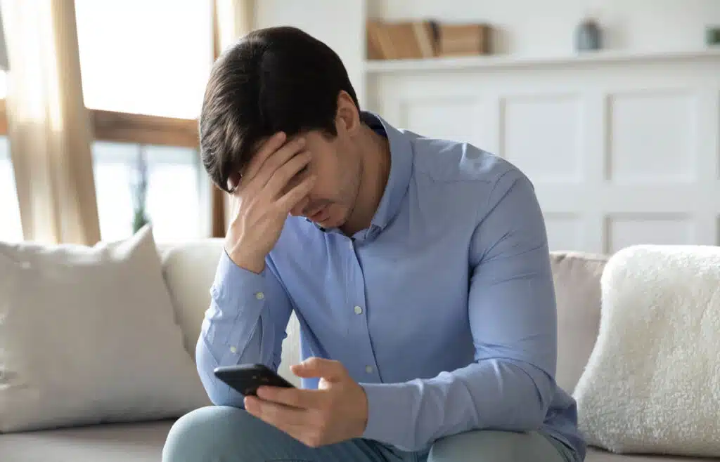 A frusturated young man looking at his phone, representing the Montway class action lawsuit settlement.