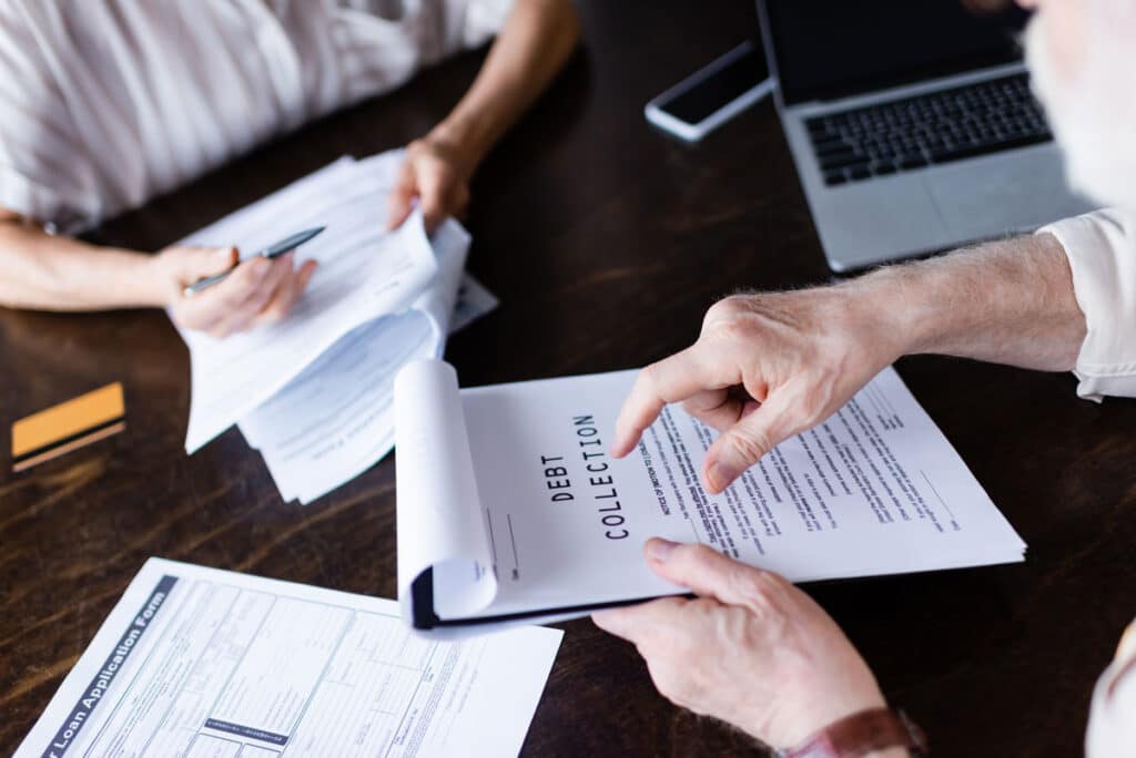 Cropped view of senior man pointing at paper with debt collection lettering, representing the Conservice class action settlement.