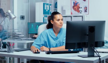 A nurse working on a computer at a nursing station, representing the Menorah Medical Center class action lawsuit settlement.