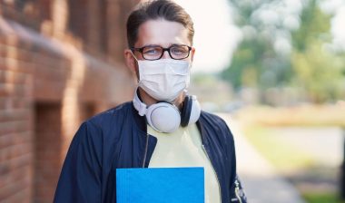 Male university student wearing a mask during the COVID-19 pandemic, representing the Quinnipiac University tuition settlement.