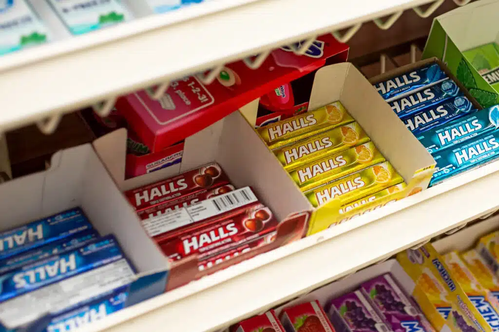 Close up of Halls packages on a grocery store shelf.