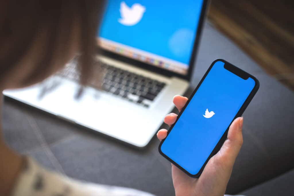 Woman using smartphone with twitter application displayed on screen, representing the Twitter hack data breach.