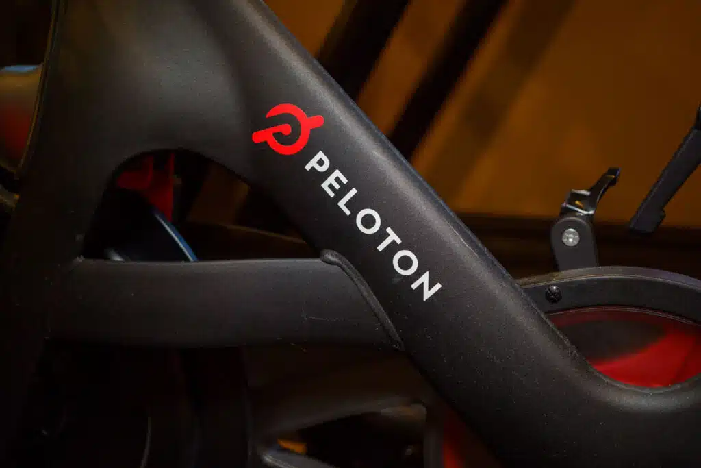 Peloton logo on the base of flagship stationary exercise bike setup for fitness riding use.