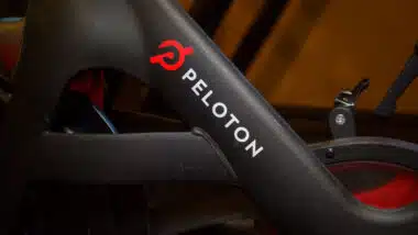 Peloton logo on the base of flagship stationary exercise bike setup for fitness riding use.
