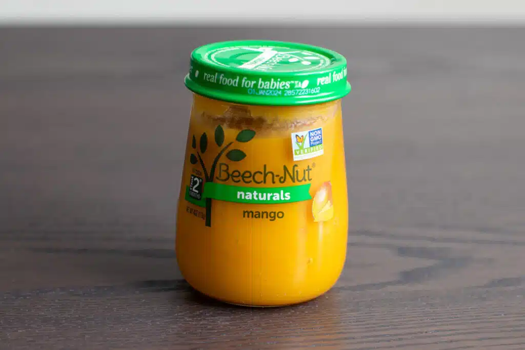 A glass jar of Beech-nut Naturals Mango puree on the table.