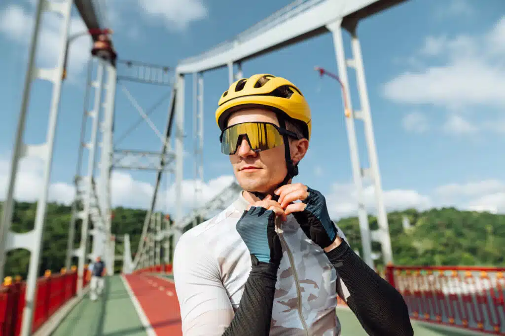 A male cyclist putting on a bike helmet.