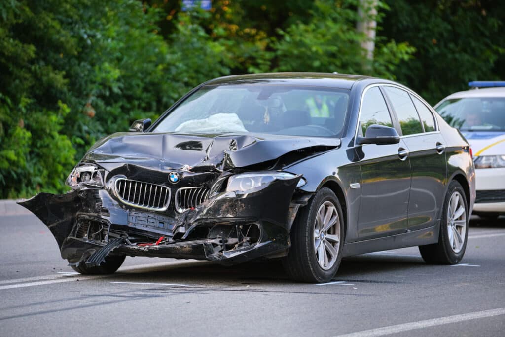 Black vehicle with damage on the front bumper, representing the American Family insurance total loss class action settlement.