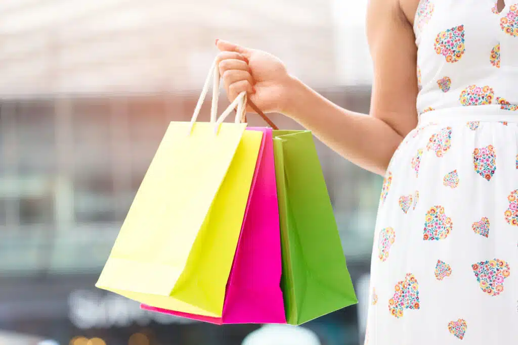 Close up of a womans arm holding shopping bags.