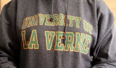A person wears a grey University of La Verne hoodie with green-and-yellow lettering, representing the tuition settlement.