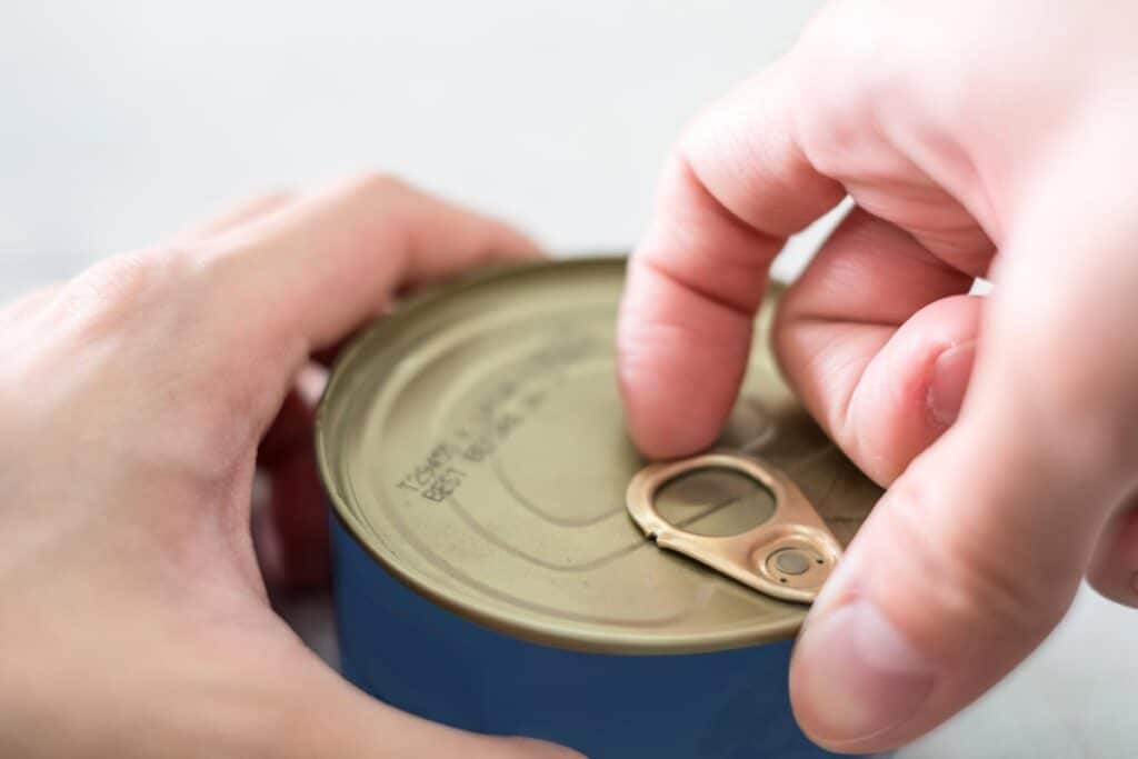 Close up of hands opening canned food.