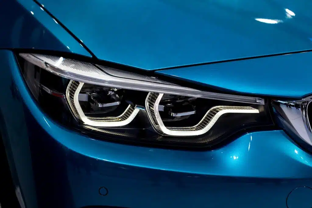 Cose up of a headlight on a luxurious blue car.
