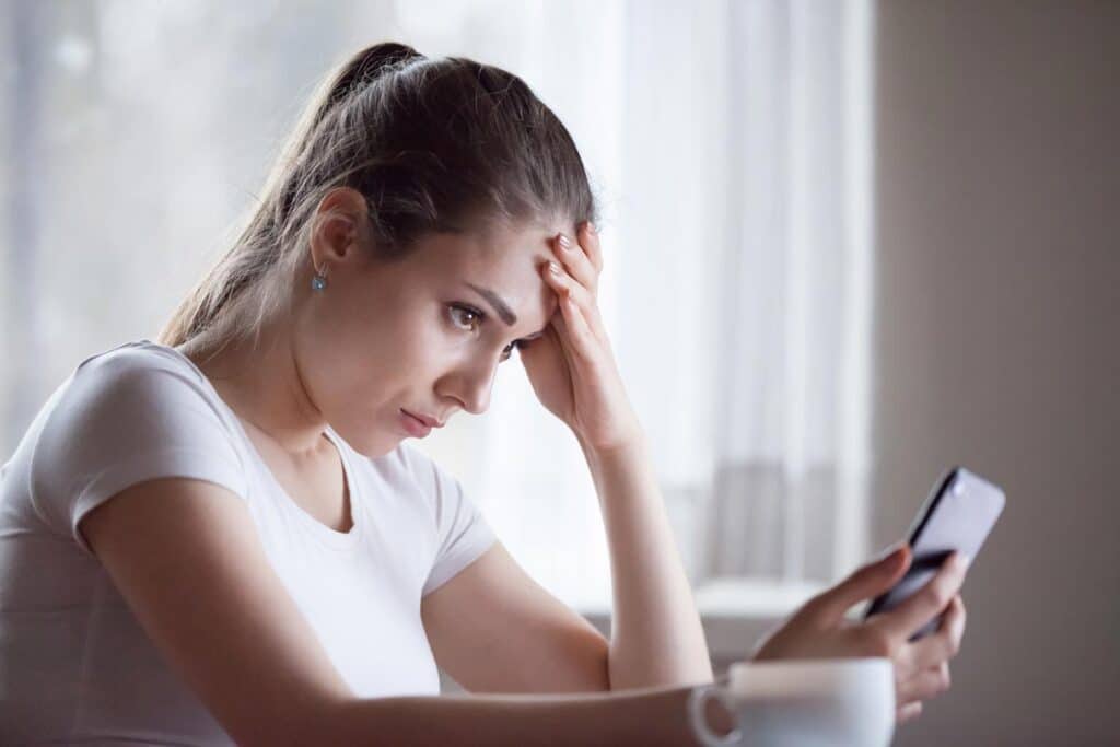 Angry young woman looking at smartphone frustrated by telemarketing text message, representing the SmileDirectClub class action lawsuit settlement.