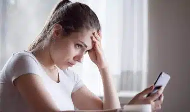 Angry young woman looking at smartphone frustrated by telemarketing text message, representing the SmileDirectClub class action lawsuit settlement.