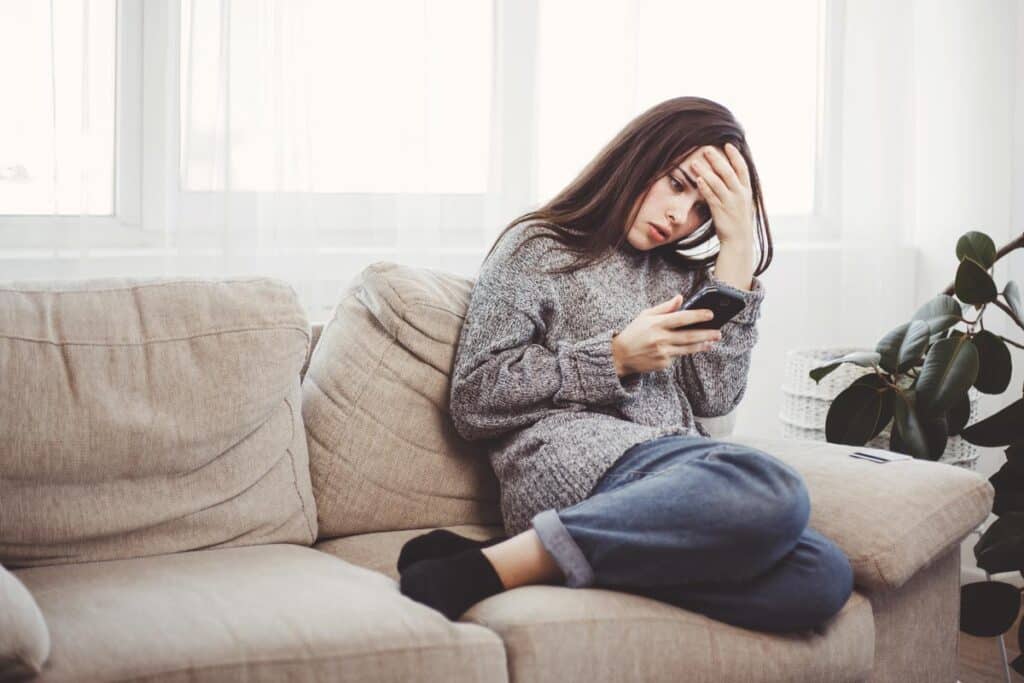 Frustrated woman reading message on a smartphone.