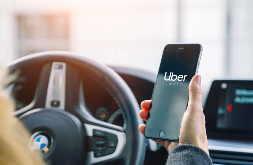 Uber driver holding his smartphone in car.