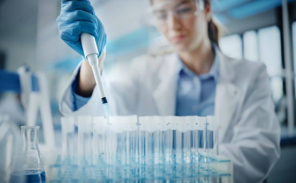 Female Scientist in Goggles Using Micro Pipette for Test Analysis, representing the Massachusetts drug conviction class action lawsuit settlement.