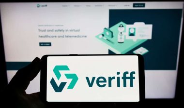 Person holding smartphone with logo of Estonian identity verification company Veriff on screen in front of website, representing the Veriff BIPA class action settlement.