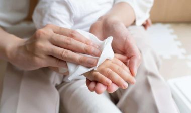A women wipes baby's arm with wet tissue.