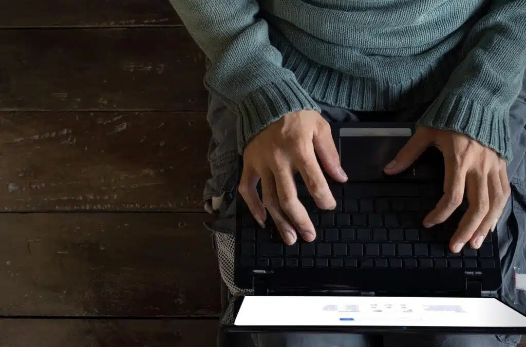Top view male hands using Laptop sitting on a wooden floor.