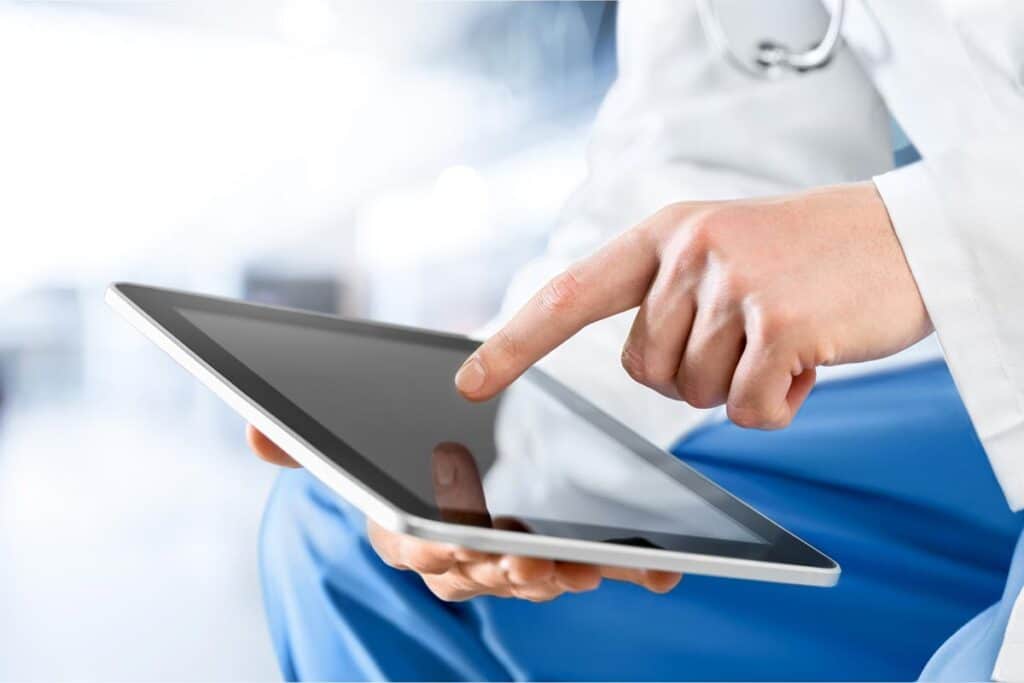 Close-up of a doctor's hands using a tablet, representing the UMass Memorial Health (UMMHC) data breach class action lawsuit settlement.