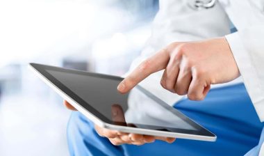 Close up of a doctors hands using a tablet, representing the UMass Memorial Health data breach settlement.