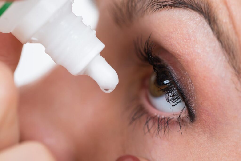 Close up of a woman putting eye drops in her eyes, representing the eye drops and ointment recall