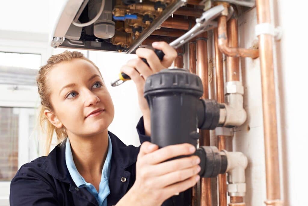 Female Plumber Working On Central Heating Boiler, representing the Focus Plumbing EEOC settlement.