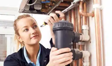 Female Plumber Working On Central Heating Boiler, representing the Focus Plumbing EEOC settlement.