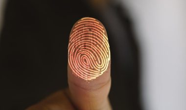 Close up of a thumb pushed against a lens with a fingerprint overlay.