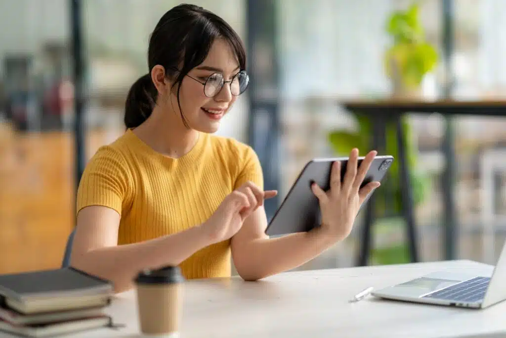 A woman in glasses smiles while using a tablet, representing March settlement deadlines.