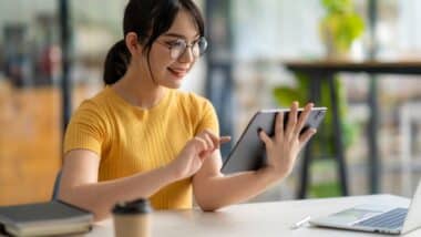 A woman in glasses smiles while using a tablet, representing March settlement deadlines.