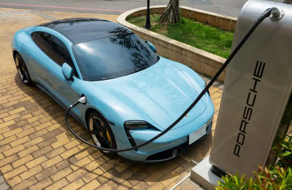 Blue Porsche Taycan turbo EV charging at Porsche branded charging station