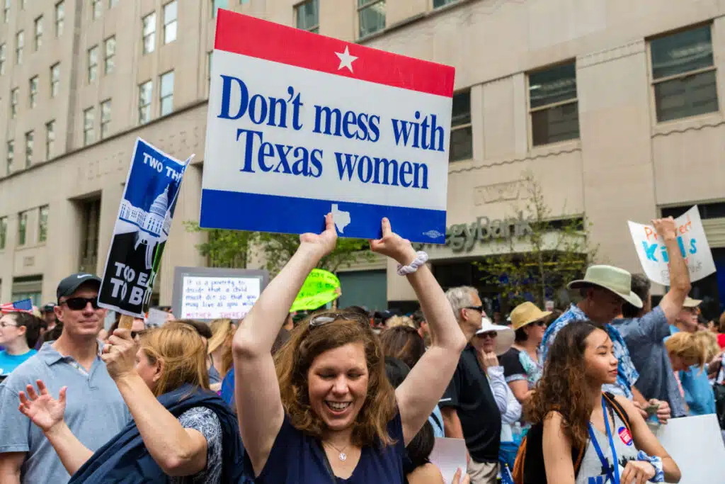 A woman at a protest holds up a sign that reads, "Don't mess with Texas women," representing the Texas abortion lawsuit.