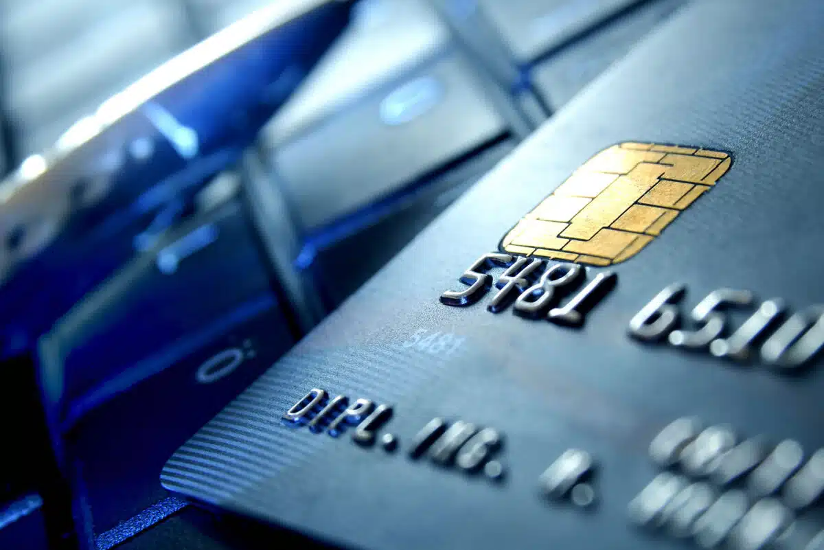 A pen & bank card lie on a keyboard, representing the Envision Credit Union data breach class action lawsuit settlement.