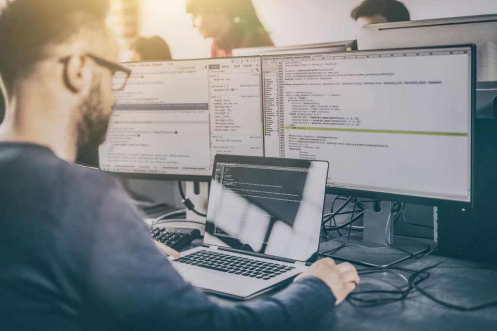 Man working on a computer with 3 screens