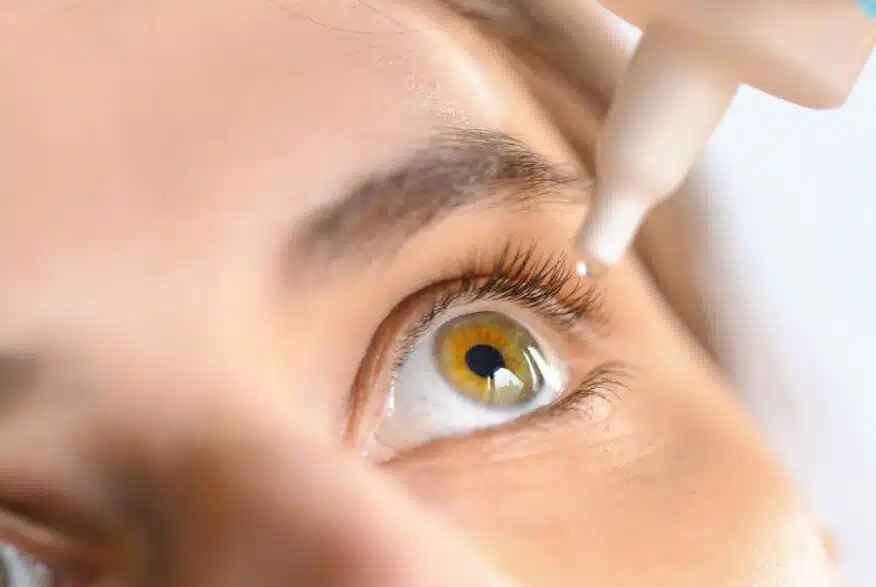 A woman applying eye drops