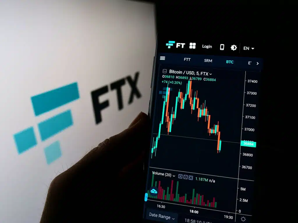 FTX logo and cell phone showing the FTX stock going down.
