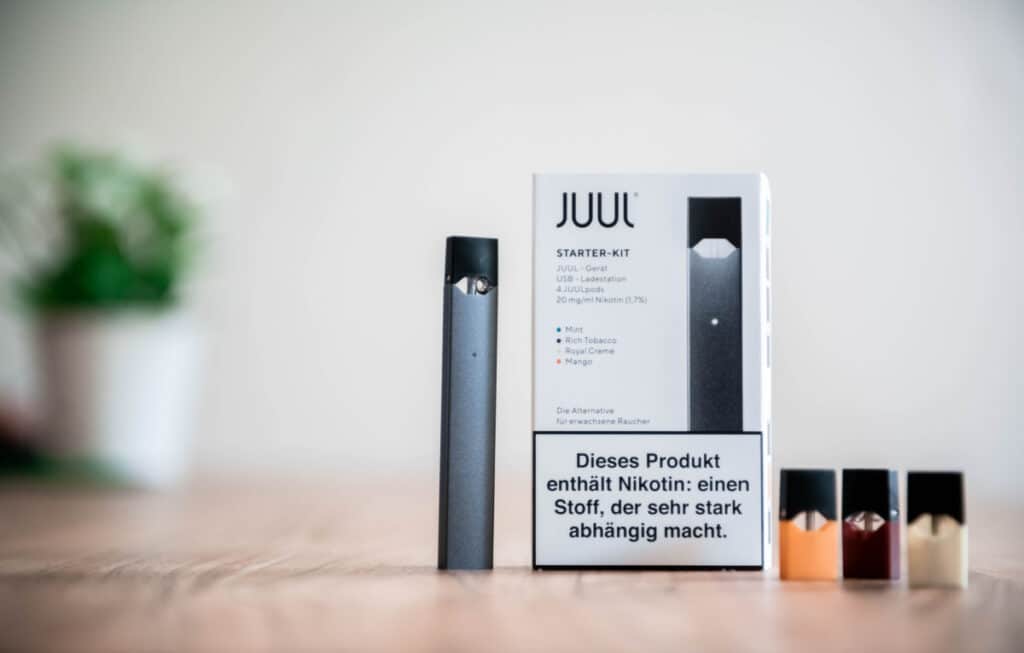 Juul vaping device with cartridges on deskrepresenting the Juul class action lawsuit settlement.