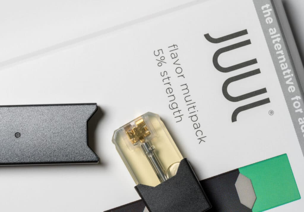 Juul vaping device laying on Juul cartridge box