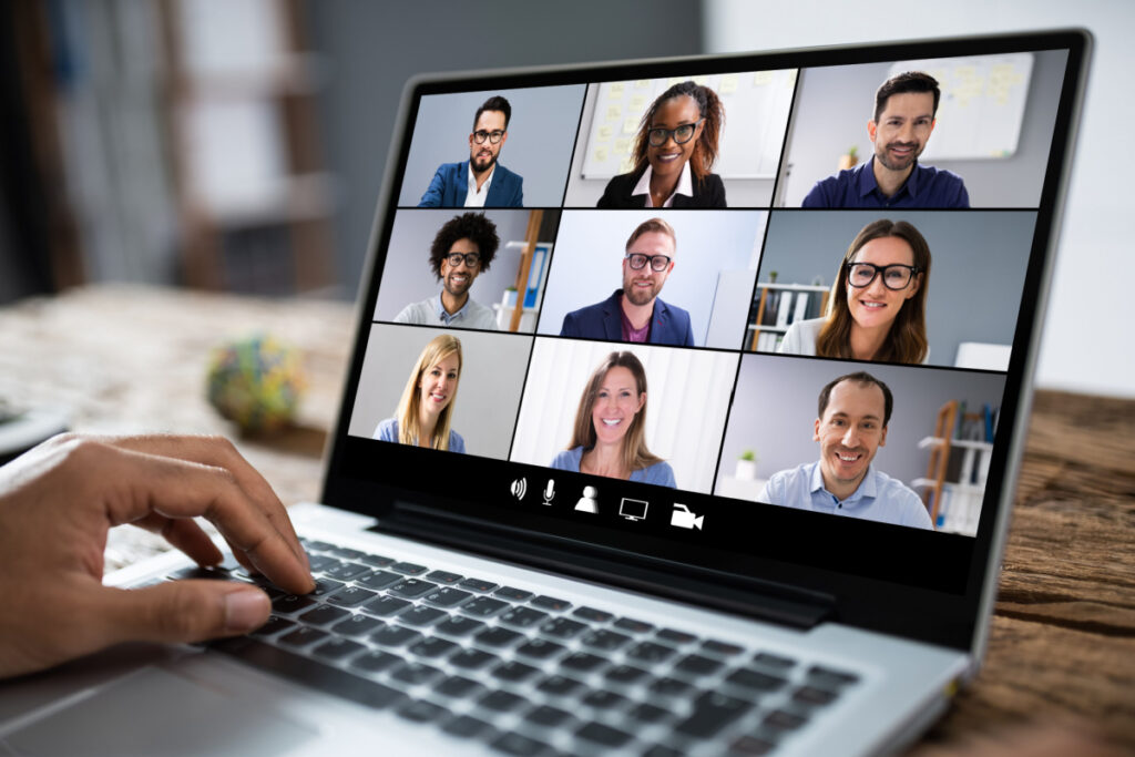 A person uses a laptop showing people in video conferencing squares, representing remote work.